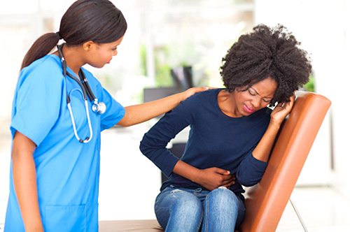 A doctor comforts a young woman suffering from stomach pain