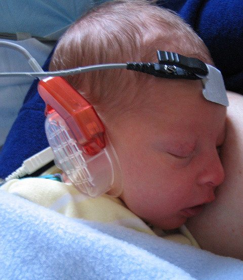 Infant undergoing a newborn hearing test while sleeping.