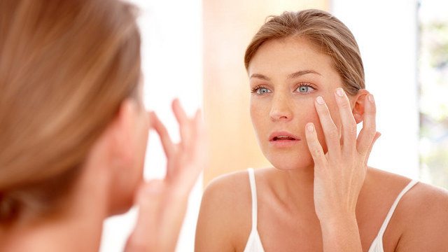 Woman applying moisturizer to face